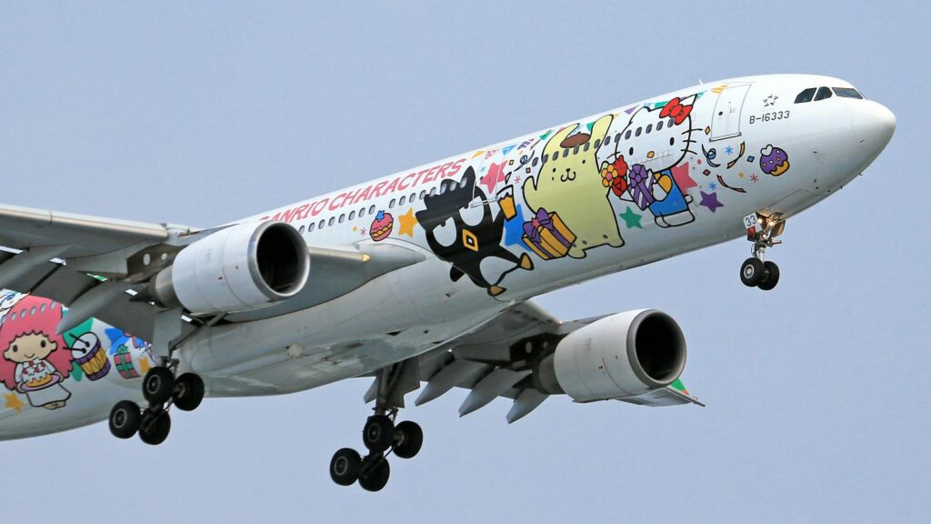Airplane adorned with vibrant Sanrio characters, soaring in clear skies.